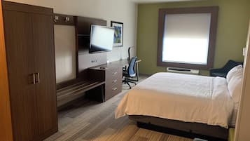 Une chambre d’hôtel comprenant un lit, un bureau avec une chaise, une télévision et une armoire.