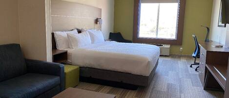 A hotel room with a bed, a desk, a chair, and a sofa.