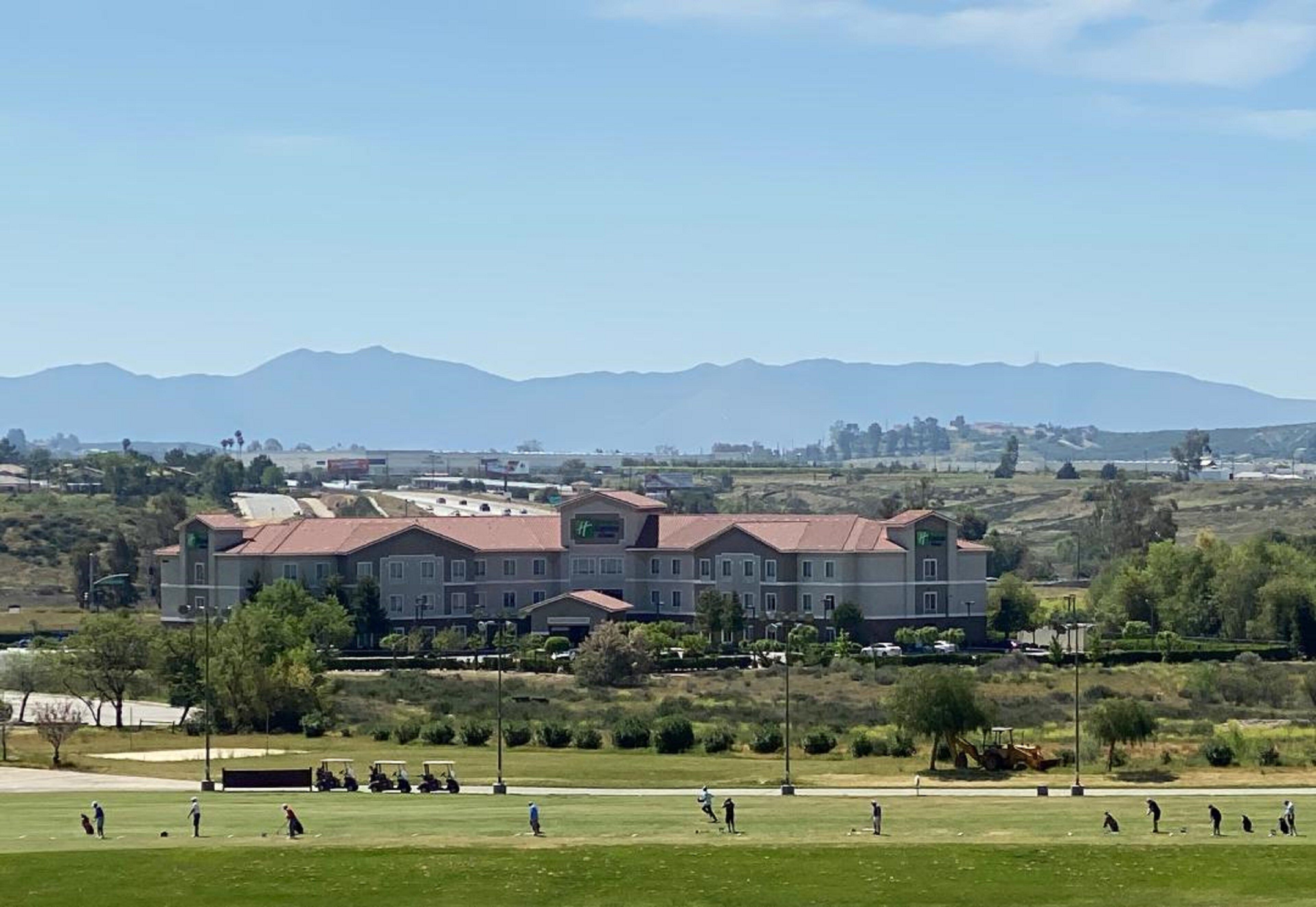 A hotel with multiple buildings, a golf course, and mountains in the background.