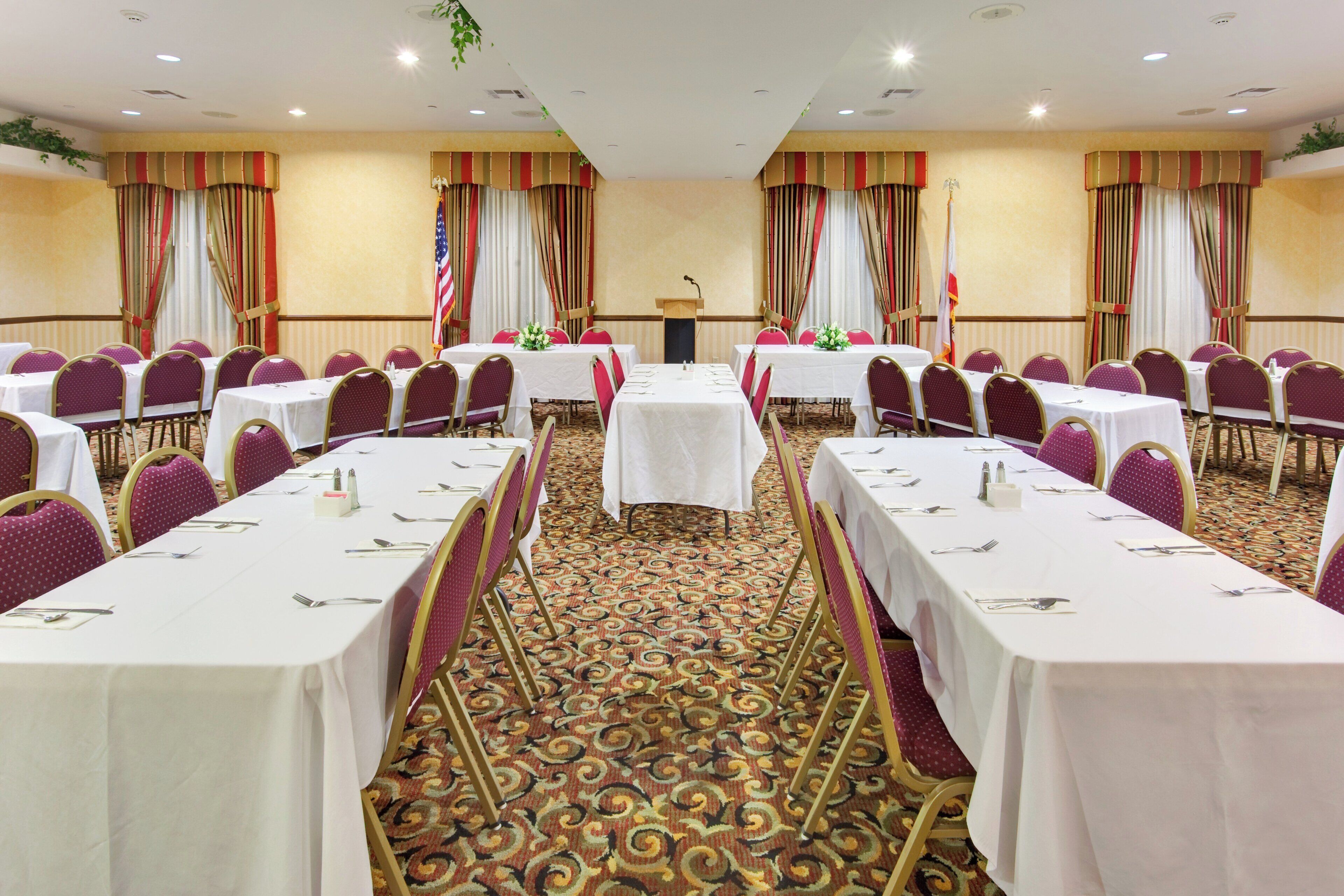 A conference room with multiple tables, chairs, and a podium.