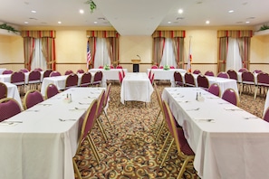 A conference room with multiple tables, chairs, and a podium.
