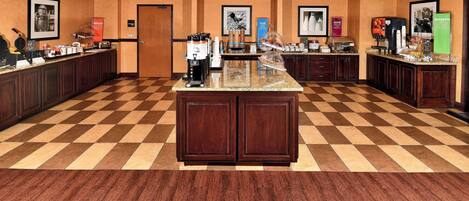 A hotel kitchen with a checkered floor, wooden cabinets, and various kitchen appliances.