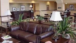 A lobby with a brown leather sofa, a reception desk, and several chairs. - Hampton Inn & Suites Fredericksburg (Fredericksburg)