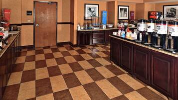 A hotel lobby with a checkered floor, a coffee station, and a reception area.