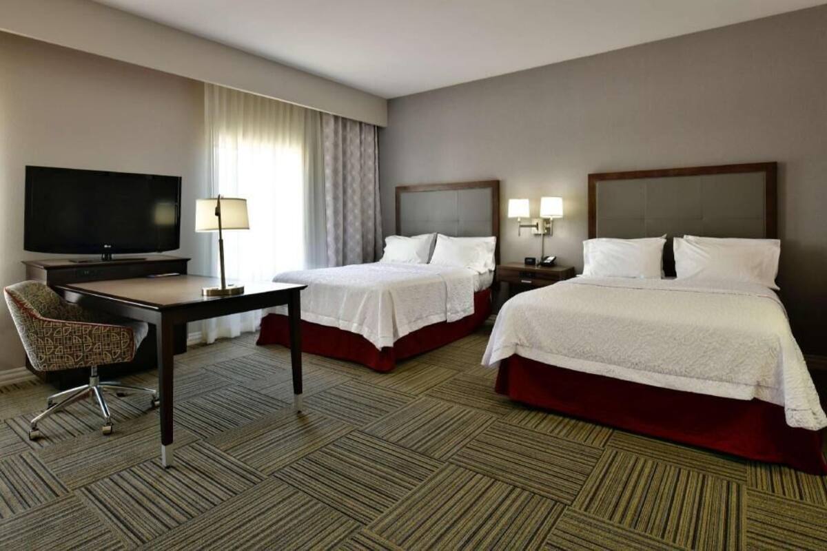 Een hotelkamer met twee bedden, een bureau, een televisie en een stoel.