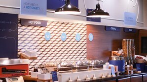 A breakfast buffet area with labeled sections for hot food, cereal, and fruit.