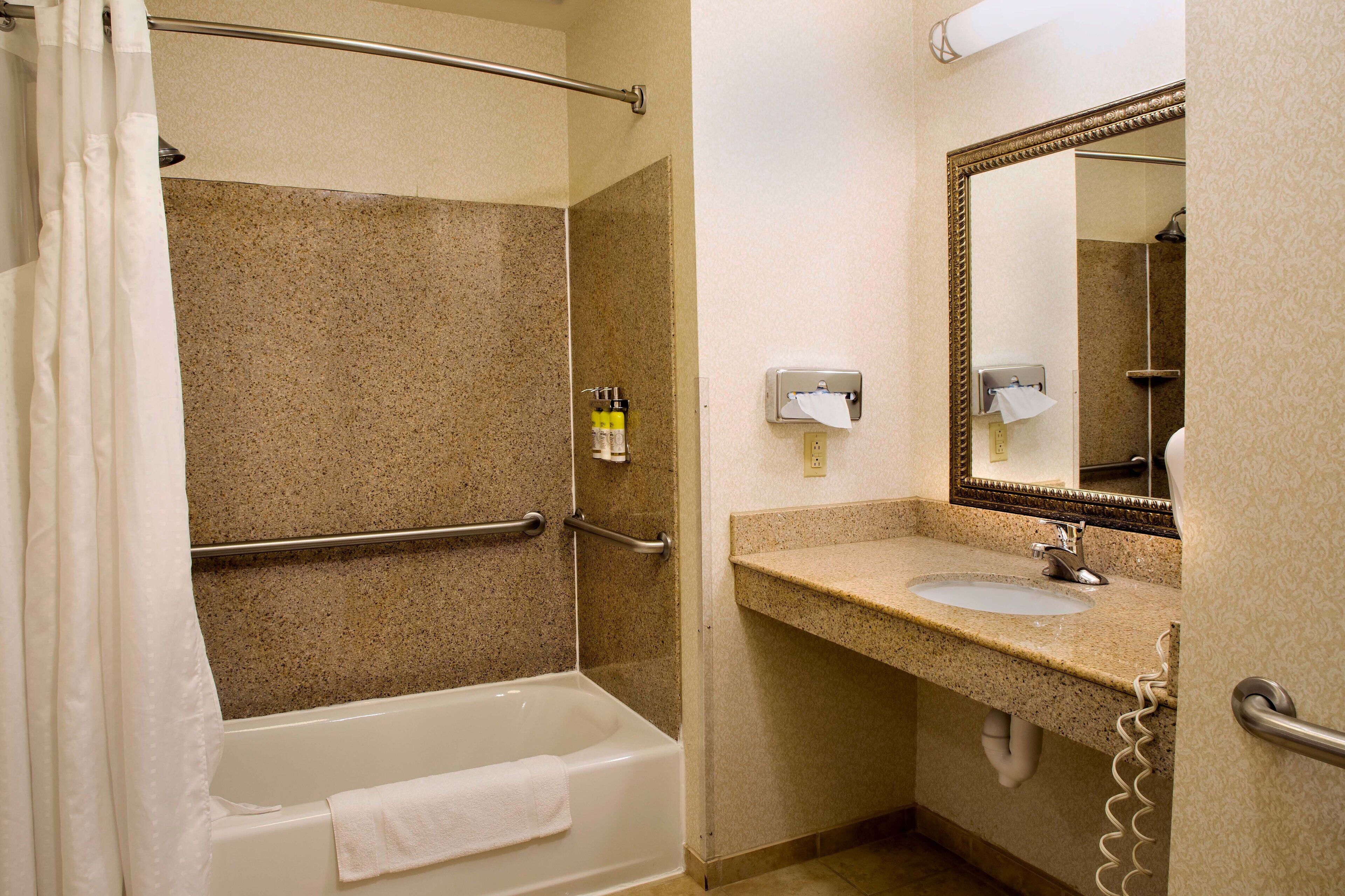 A bathroom with a bathtub, a sink, a mirror, and a towel rack.