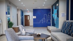 A modern lobby with seating, a map mural, and a sign indicating complimentary breakfast hours.