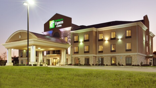 A Holiday Inn Express & Suites hotel with a covered entrance, stone facade, and multiple windows.
