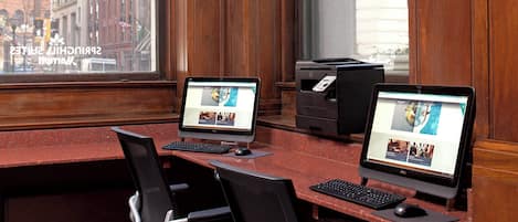 Una sala de conferencias con dos computadoras de escritorio, una impresora y dos sillas.