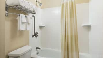 A bathroom with a toilet, a bathtub, a shower, and a towel rack with towels.