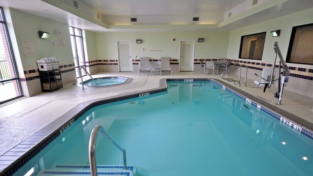 Une piscine avec un panneau indiquant qu’il est interdit de plonger, des chaises longues et un jacuzzi.