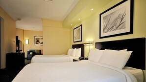 Une chambre d’hôtel avec deux lits, un bureau, une chaise et un téléviseur.