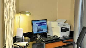 A hotel room desk with a computer, printer, and office chair.