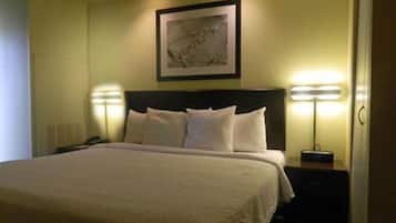 A hotel room with a large bed, two bedside lamps, a framed picture on the wall, and a nightstand.