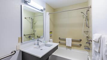 A bathroom with a white sink, a bathtub, a shower with a grab bar, a mirror, and a towel rack.