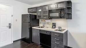 A modern kitchen with dark wood cabinets, a stainless steel refrigerator, a microwave, and a dishwasher.