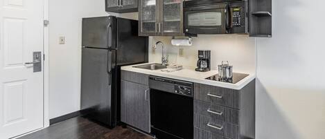 Una cocina moderna con armarios de madera oscura, un refrigerador de acero inoxidable, un microondas y un lavavajillas.
