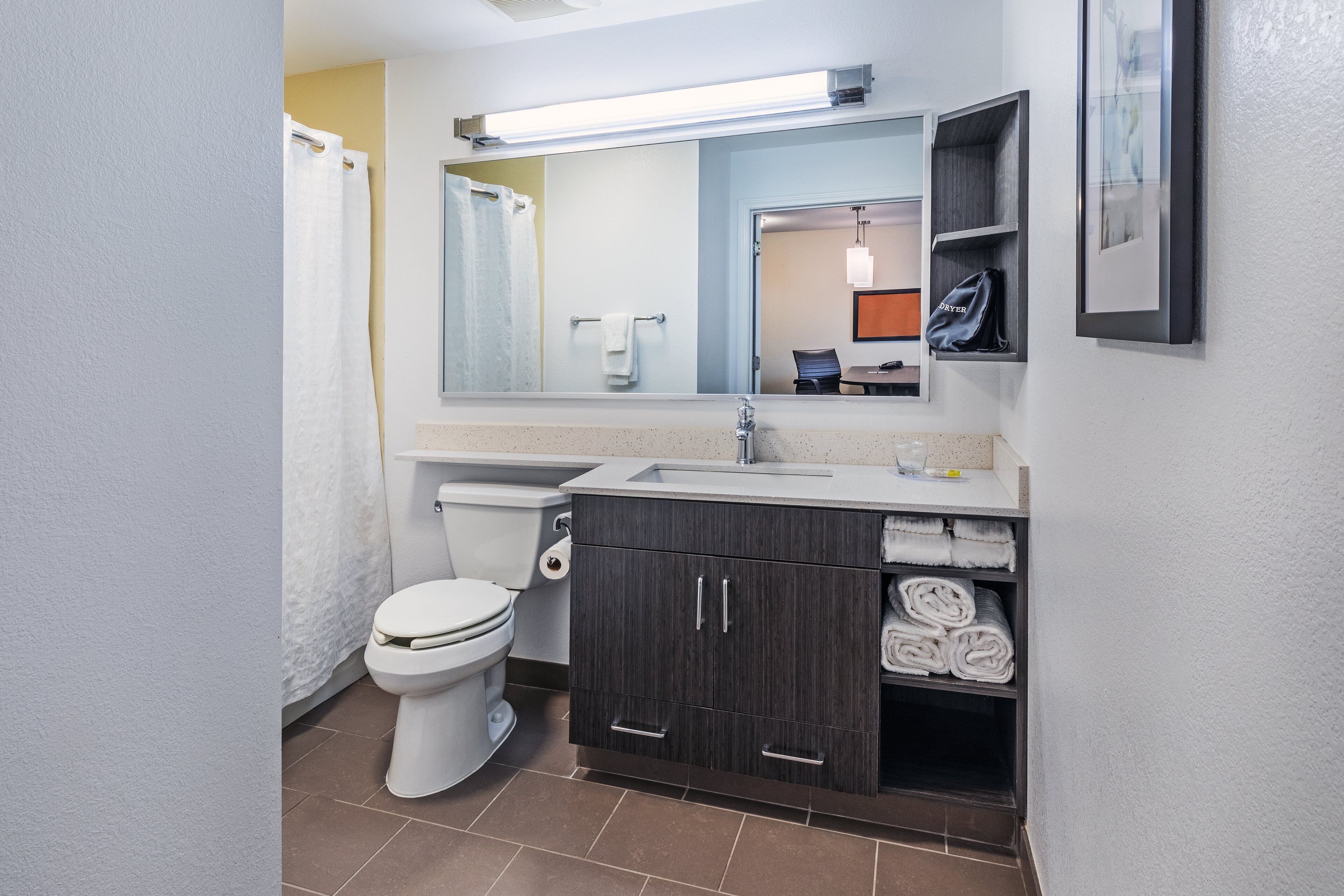 Un baño moderno con inodoro, lavamanos y armarios de madera oscura.