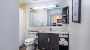 A modern bathroom with a toilet, sink, and dark wooden cabinets.