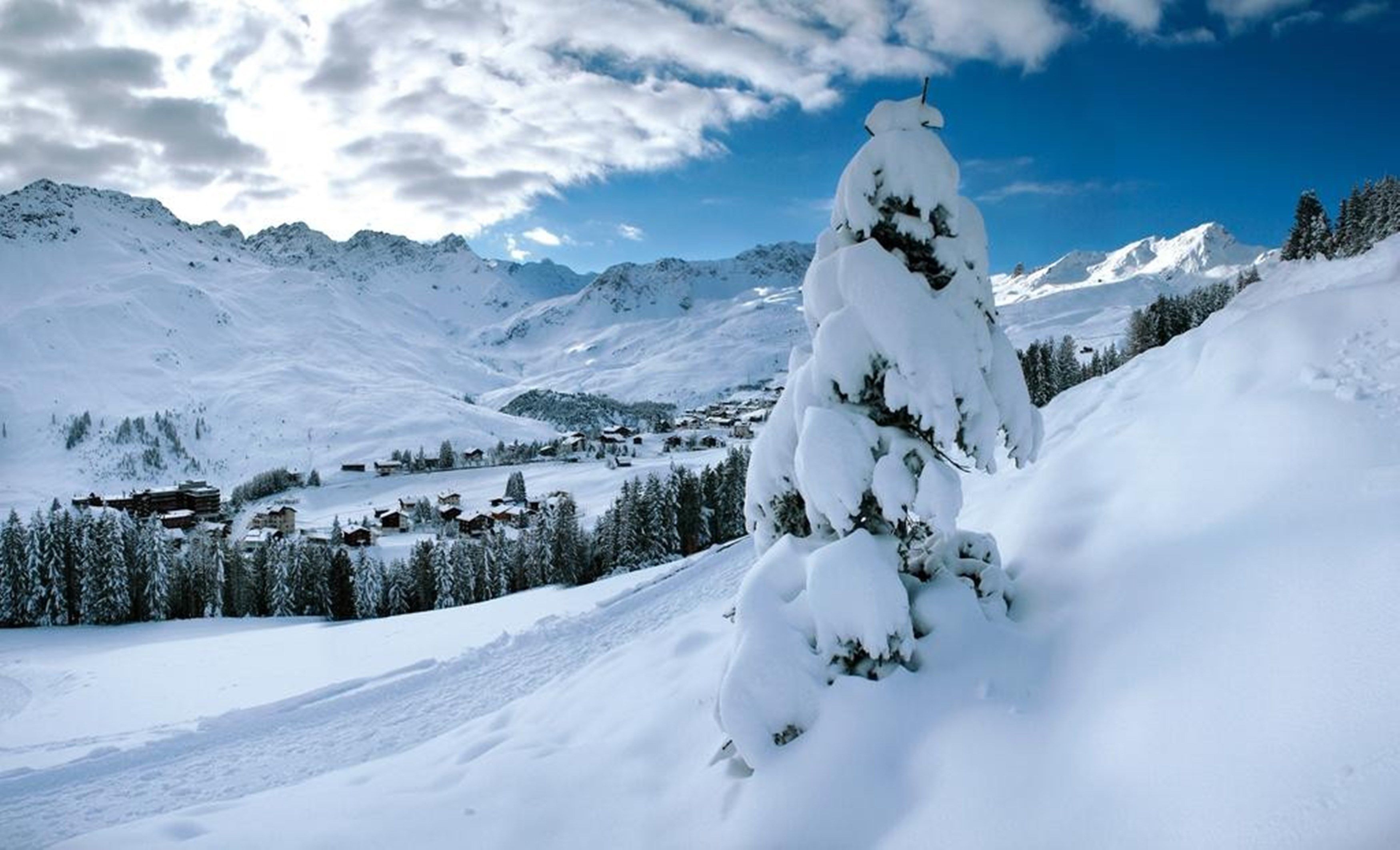 Eine verschneite Berglandschaft mit einem kleinen Dorf im Tal.