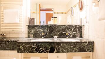 A bathroom with a black marble countertop, two sinks, a towel rack, and a mirror.
