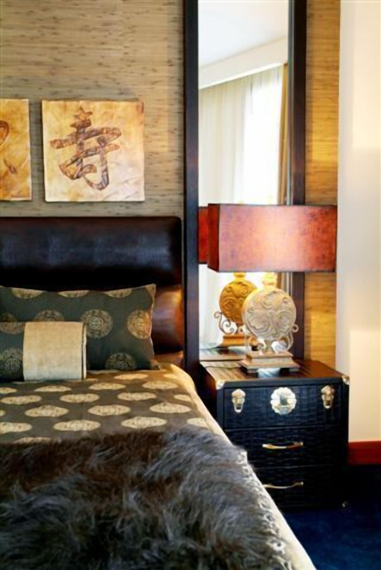 A bedroom with a bed, a nightstand, a lamp, and artwork on the wall.