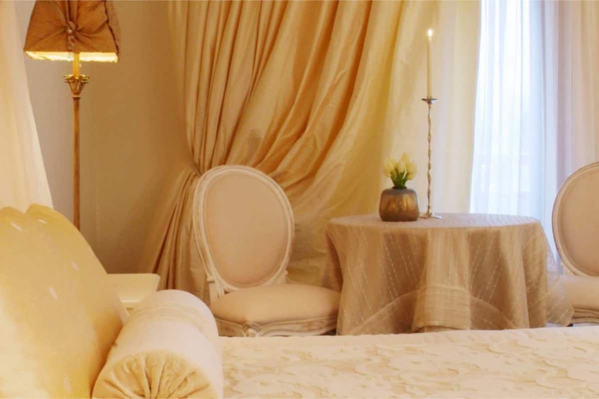 Una habitación de hotel con una cama, dos sillas, una mesita y una lámpara.