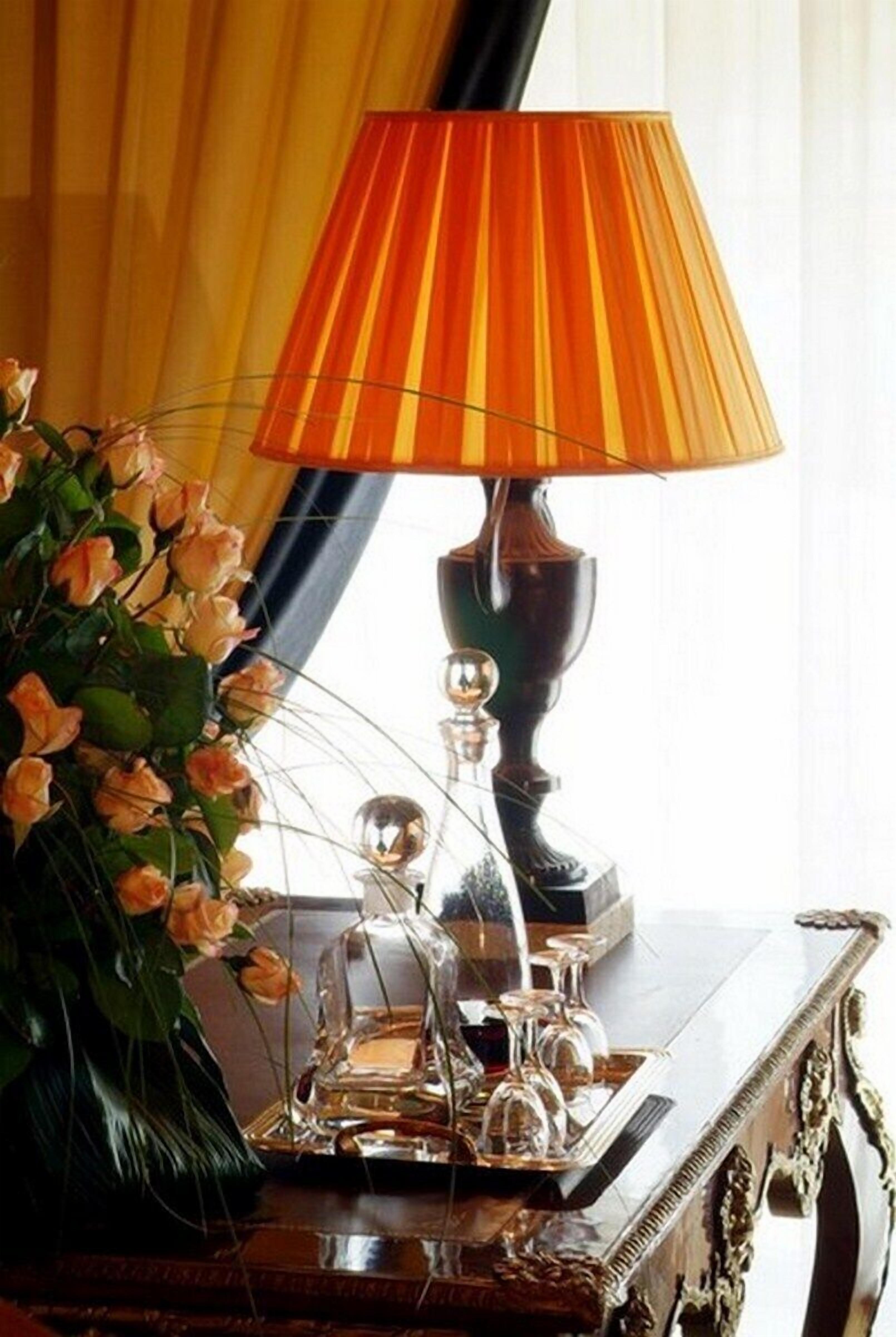 A table with a lamp, a vase of flowers, and a tray with glassware.