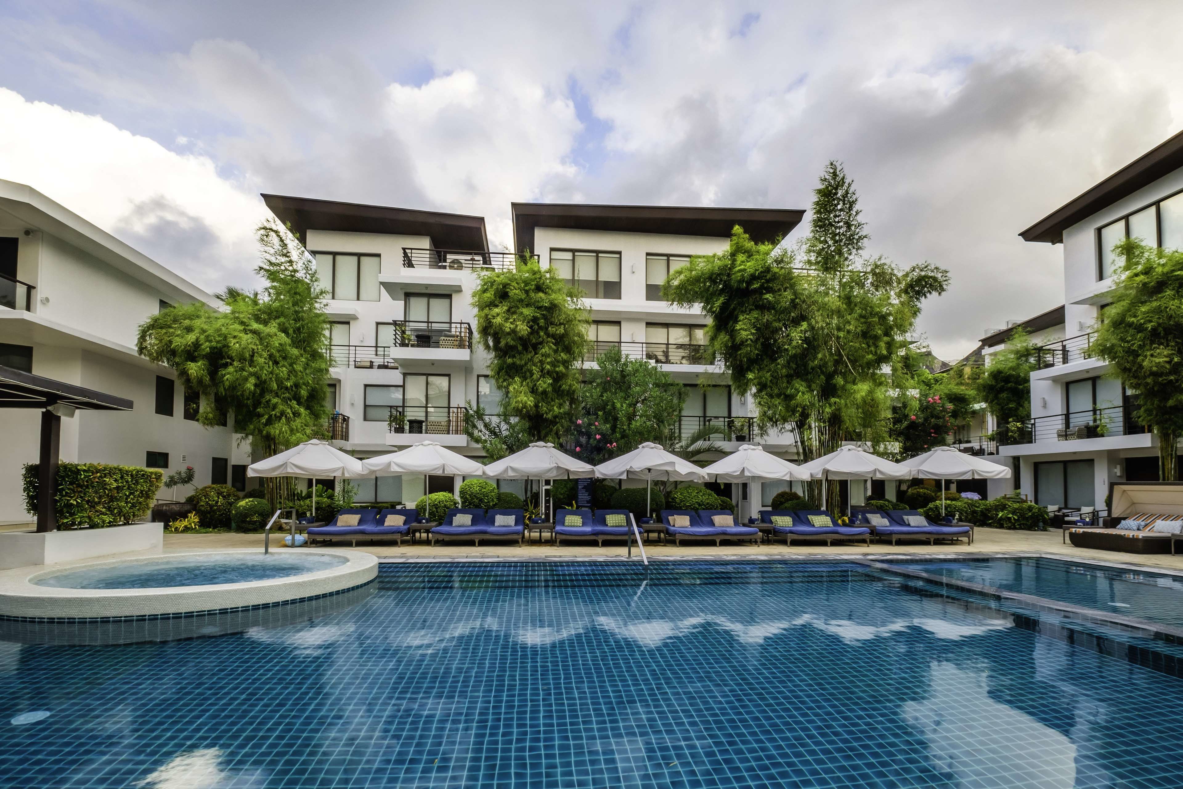 Un hôtel moderne doté d’une piscine, de chaises longues et de parasols.