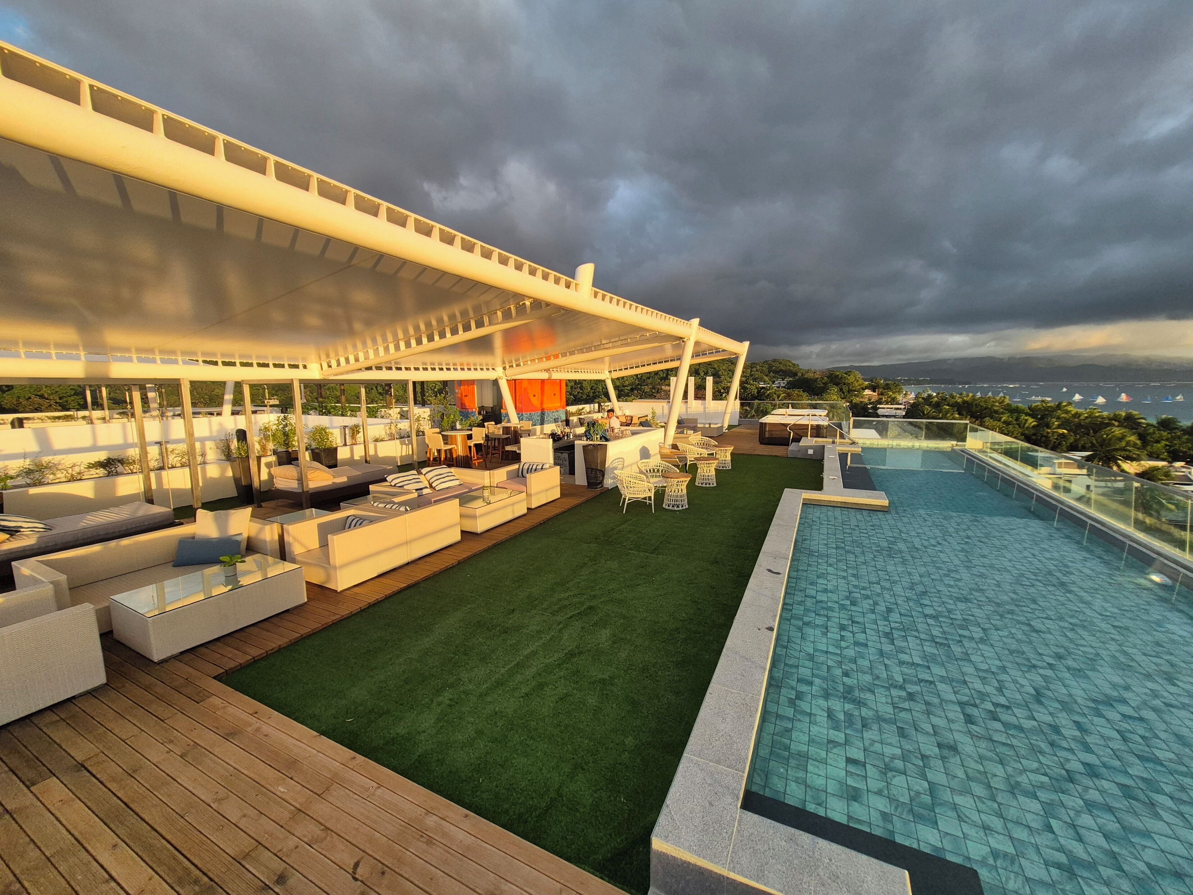 Un área de piscina en la azotea con mobiliario exterior y una zona de bar cubierta.