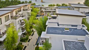 Un hôtel moderne à plusieurs étages, doté de piscines extérieures et offrant une vue sur la mer et les bateaux.