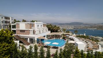 Un hôtel moderne doté d’une piscine sur le toit, d’un espace extérieur aménagé et offrant une vue sur la mer et le paysage urbain.