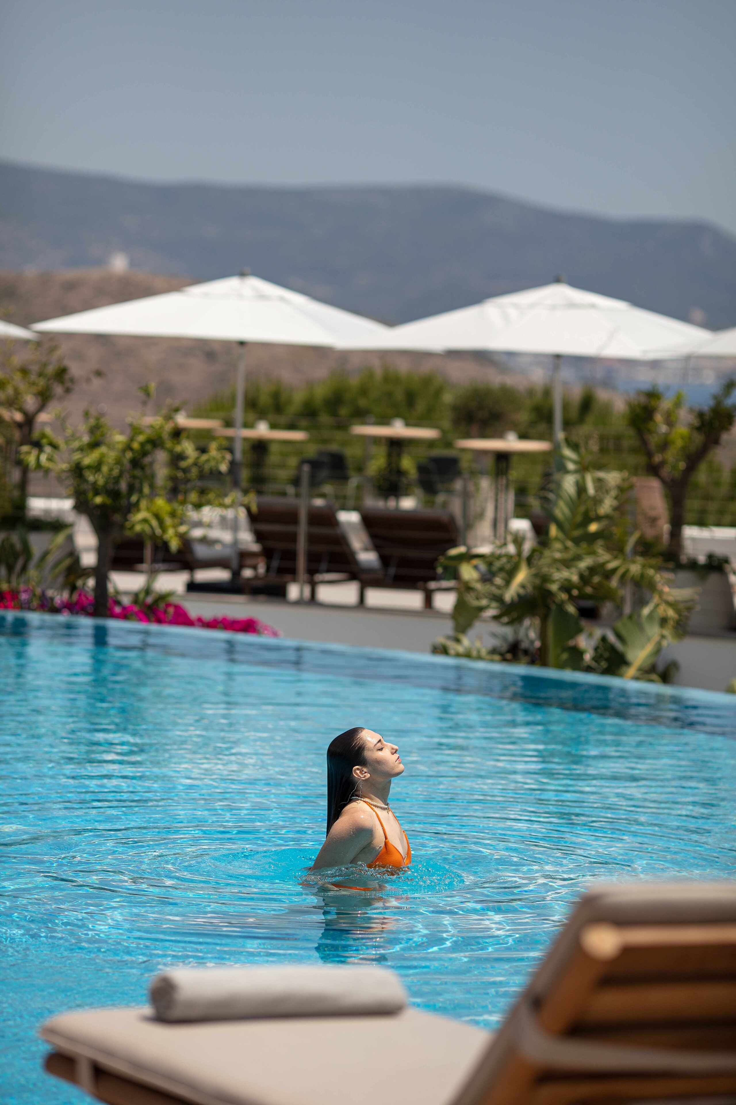 A swimming pool with lounge chairs and umbrellas in the background.