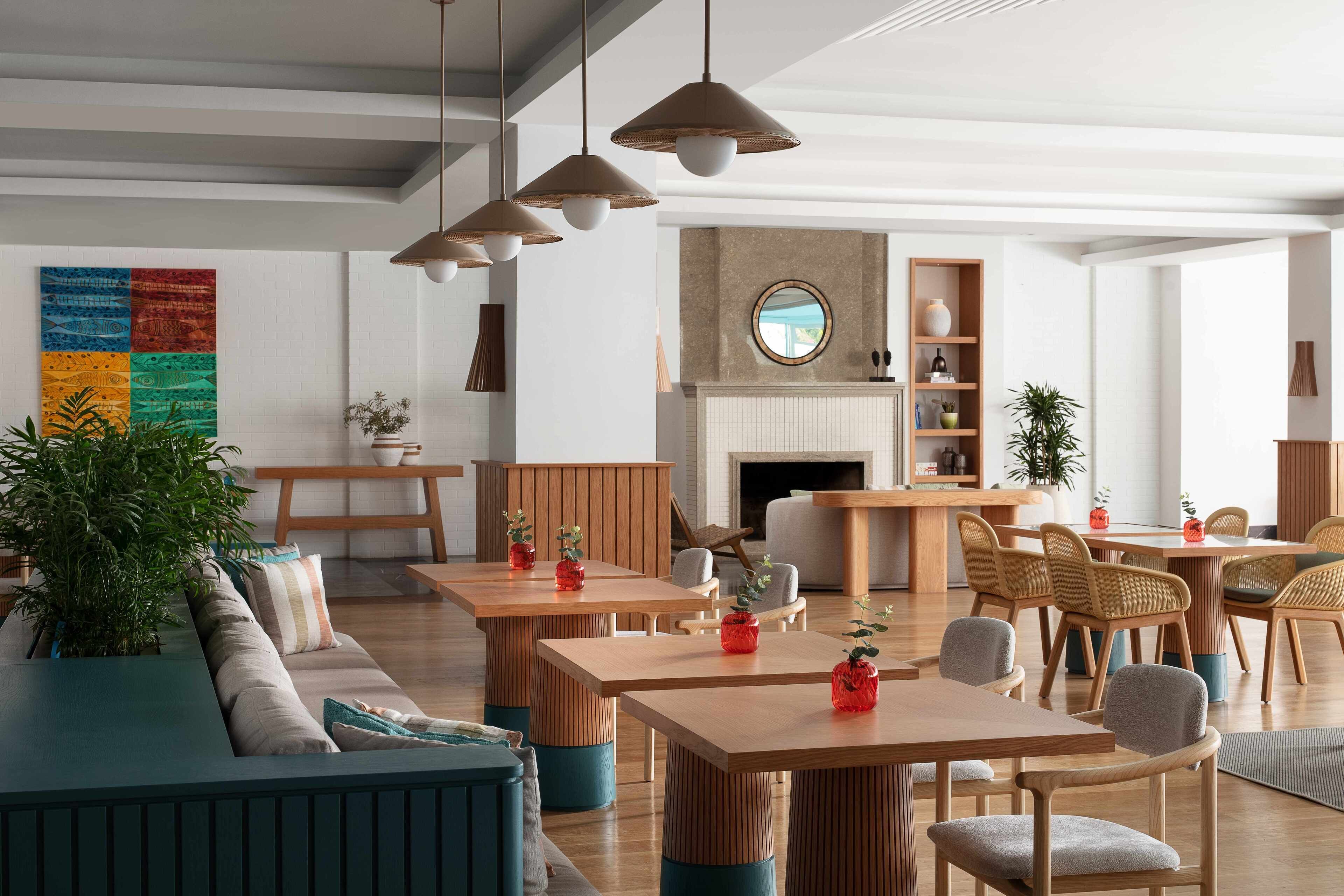 A modern interior with wooden tables and chairs, a fireplace, and a colorful wall art piece.