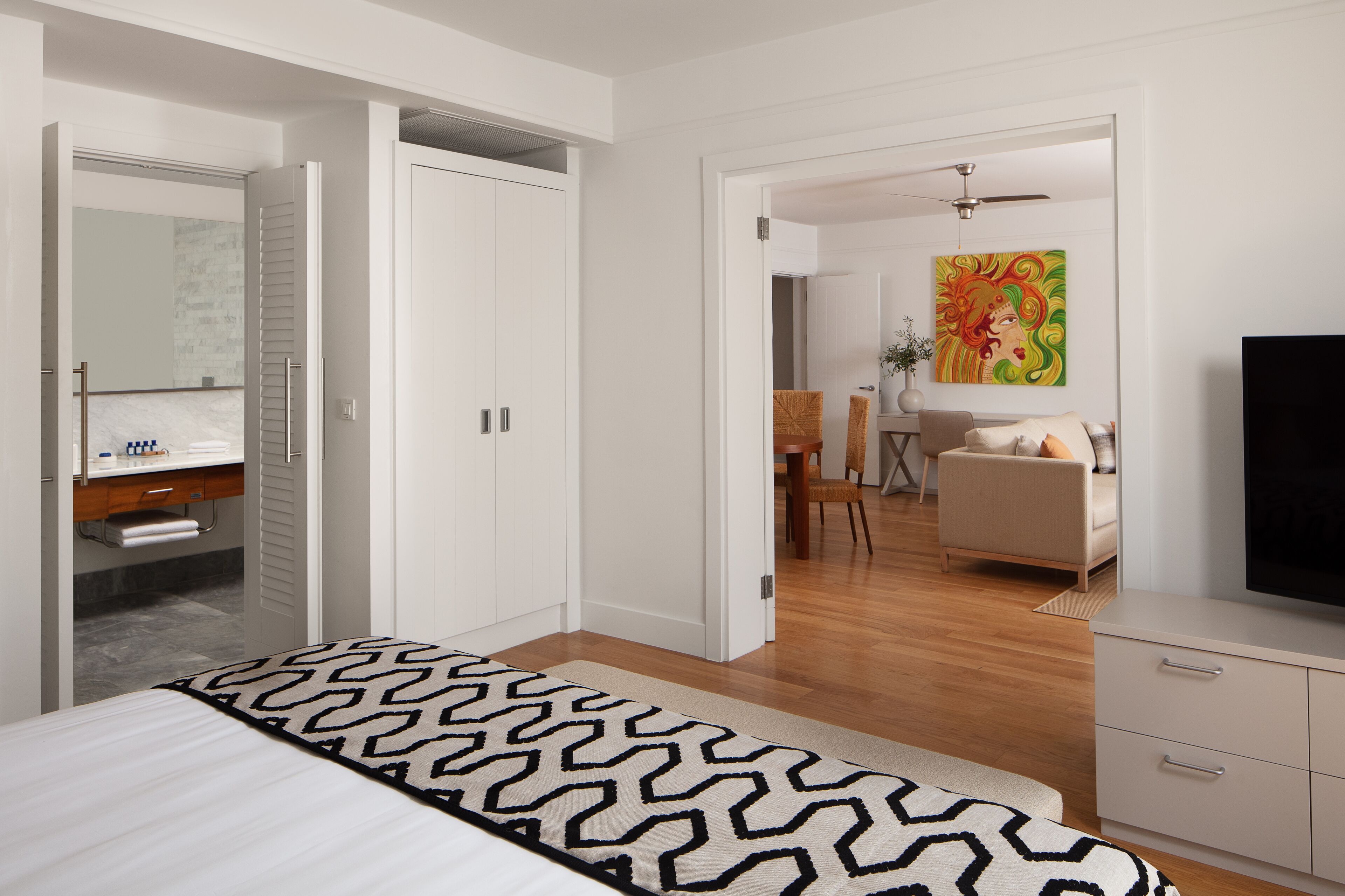 A modern hotel room with a bed, a TV, a desk, and a chair.