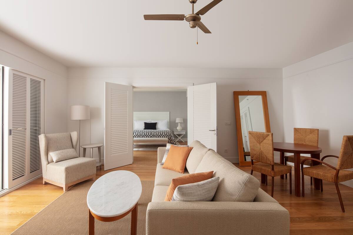 Un salon moderne comprenant un canapé, des fauteuils, une table à manger et un ventilateur de plafond.