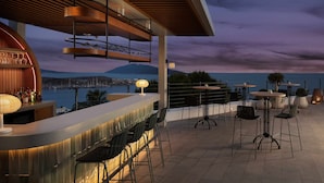 An outdoor bar area with a view of the sea and mountains, featuring bar stools and tables. -  Doria Hotel Bodrum-City Center (Bodrum)