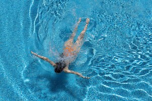 Nadador en una piscina con agua cristalina azul.