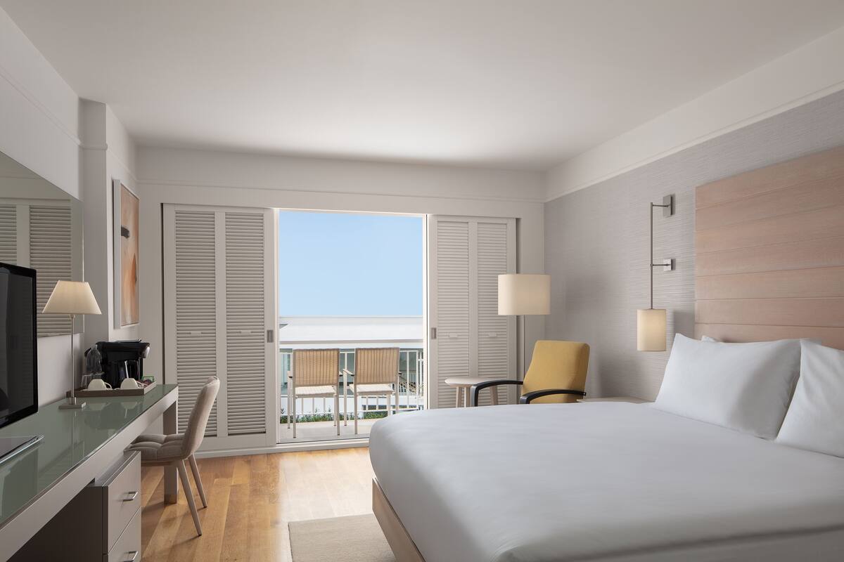 Une chambre d’hôtel avec un lit, un bureau doté d’une lampe, une chaise et une vue sur l’extérieur.