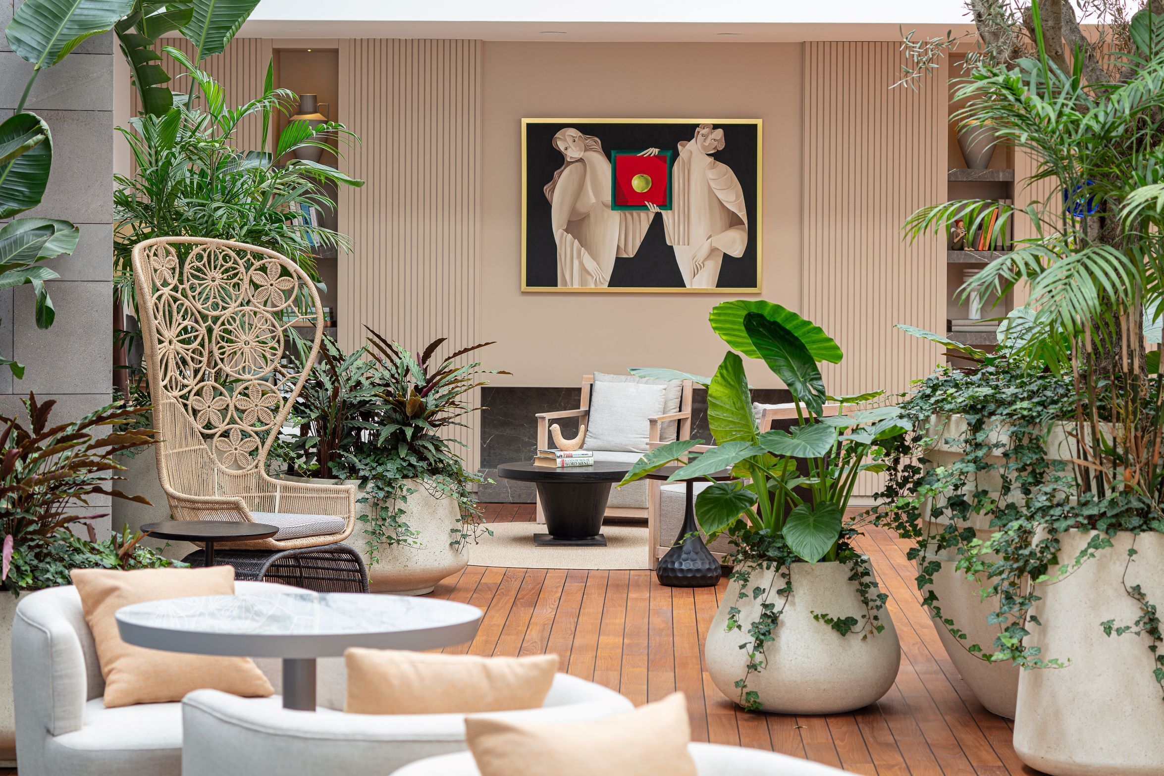 A modern outdoor seating area with wicker chairs, a round table, and large potted plants.