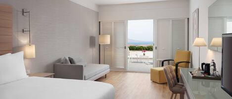 A modern hotel room with a large bed, a sofa, a dining area, and a balcony with a view.