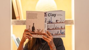 A person reading a book titled 'Clay' at a table with various dishes and a vase in the background. -  Doria Hotel Bodrum-City Center (Bodrum)