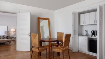 Una habitación compacta con una mesa de comedor y sillas, una kitchenette pequeña y una cama con colcha estampada.