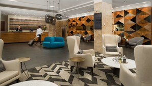 A modern lobby with a reception desk, seating area, and decorative wall panels.