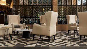 A modern lobby with a geometric patterned floor, a wine cellar visible through a glass partition, and comfortable seating areas. - Rydges Campbelltown (Campbelltown)