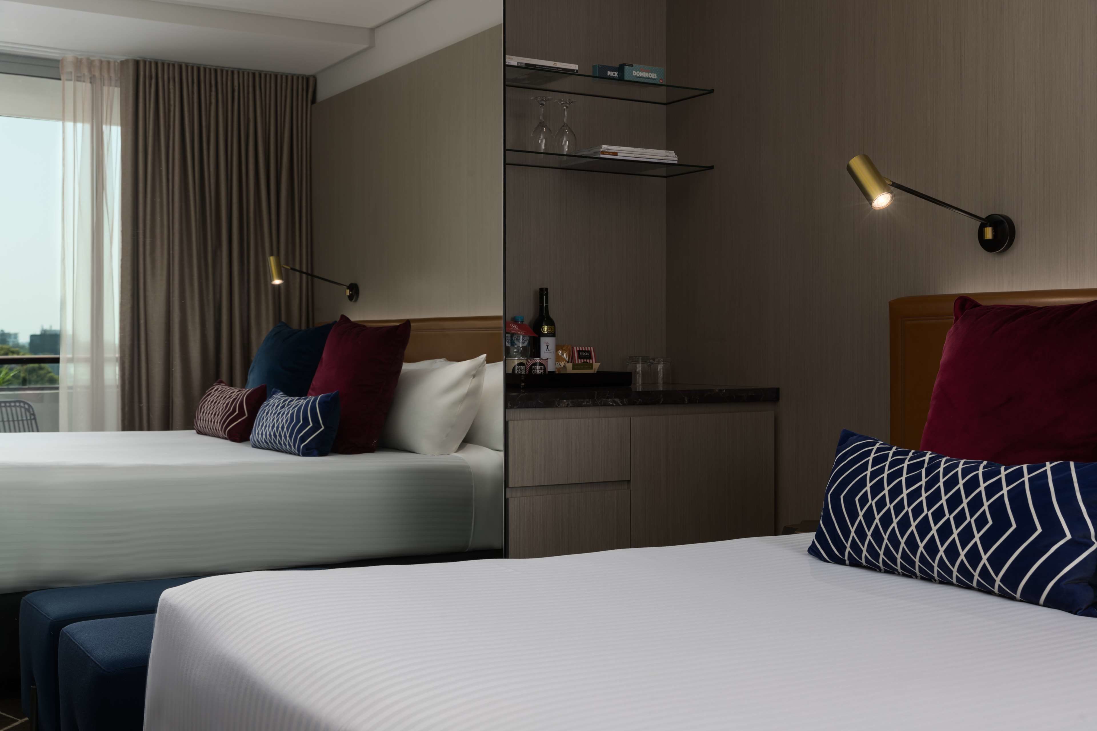 A hotel room with two beds, a minibar, and a view of the city.