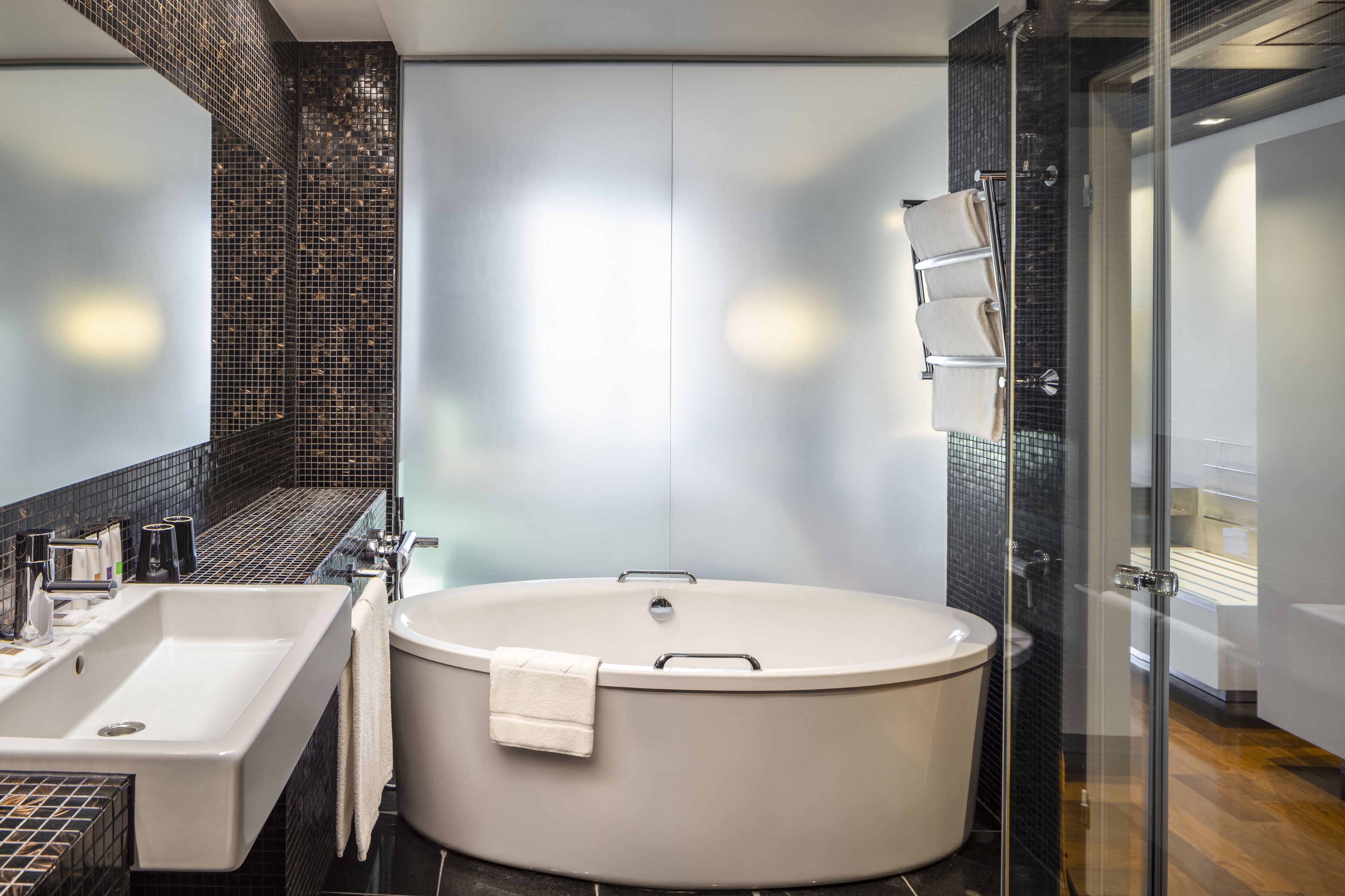 A modern bathroom with a freestanding bathtub, a large sink, and a glass shower enclosure.