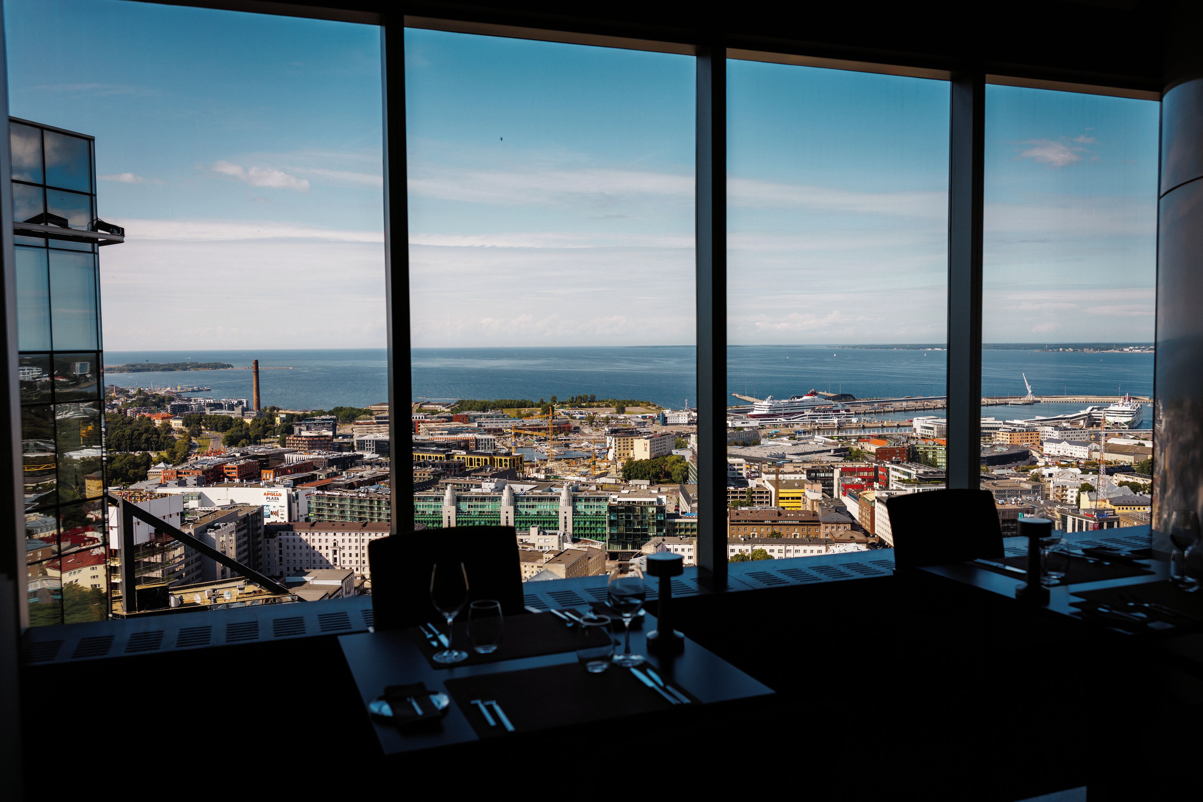 A panoramic view from a high-rise window overlooking a cityscape with a body of water in the distance.