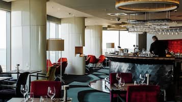 A modern restaurant interior with a bar area, seating arrangements, and a view through large windows.